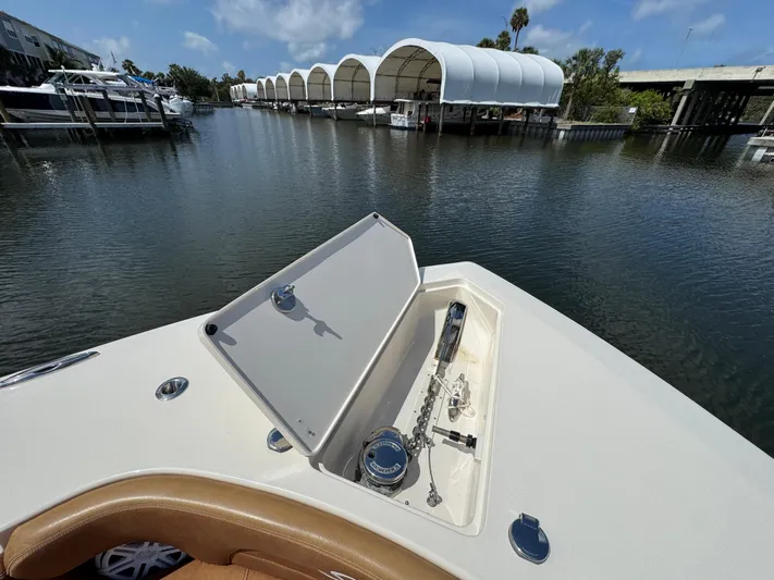  Yacht Photos Pics Bow of 2018 Scout 420 LXF boat with anchor compartment open, docked near covered slips.