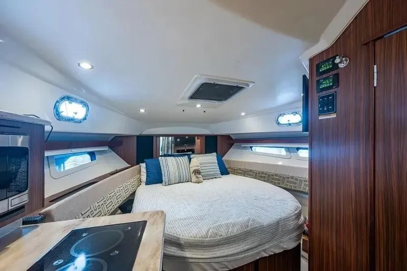  Yacht Photos Pics 2023 Pursuit OS 355 Offshore cabin interior with bed, wood paneling, and modern amenities.