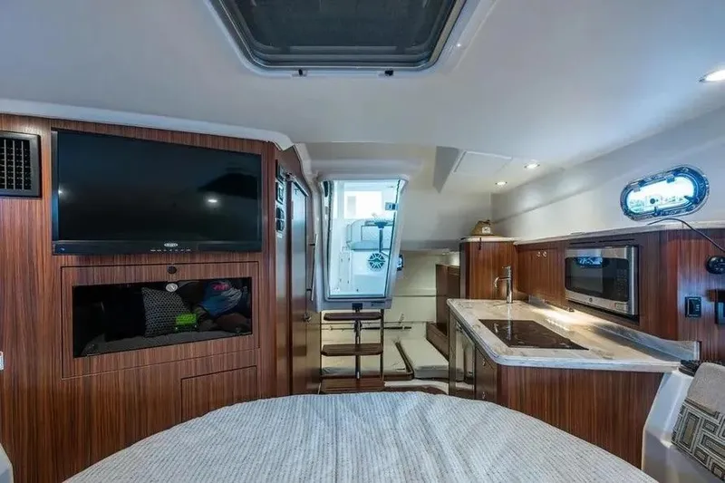  Yacht Photos Pics 2023 Pursuit OS 355 Offshore cabin interior with kitchenette, TV, and modern amenities.