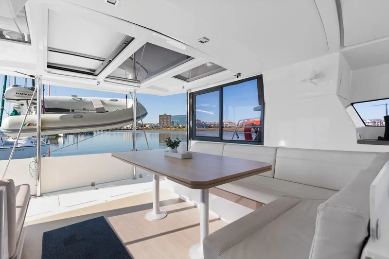 Chasing Shimmer Yacht Photos Pics Spacious interior of 2018 Bali 4.0 catamaran with seating and table, overlooking marina.