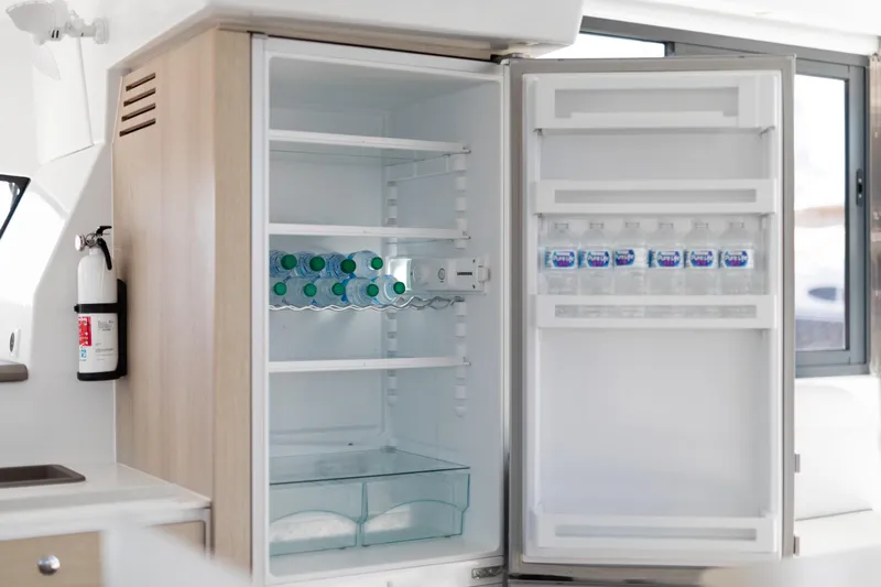 Chasing Shimmer Yacht Photos Pics Open fridge on Bali 4.0 yacht, stocked with bottled water, next to a fire extinguisher.