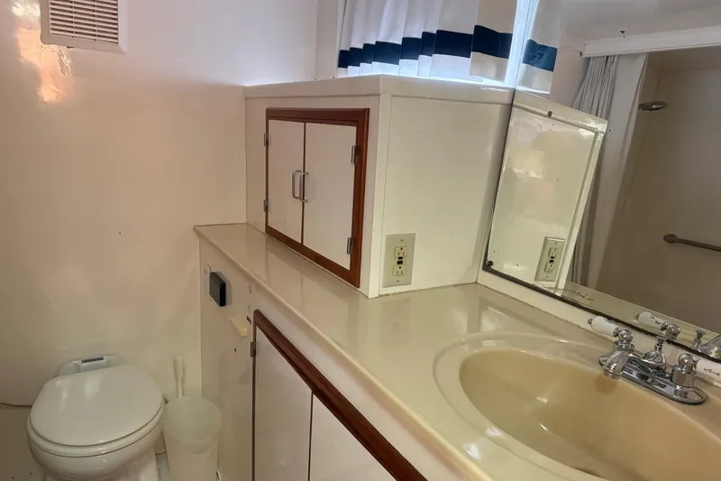 Sweet Caroline Yacht Photos Pics Bathroom interior of 1989 Jefferson Marquessa 52 yacht with sink, mirror, and storage cabinets.