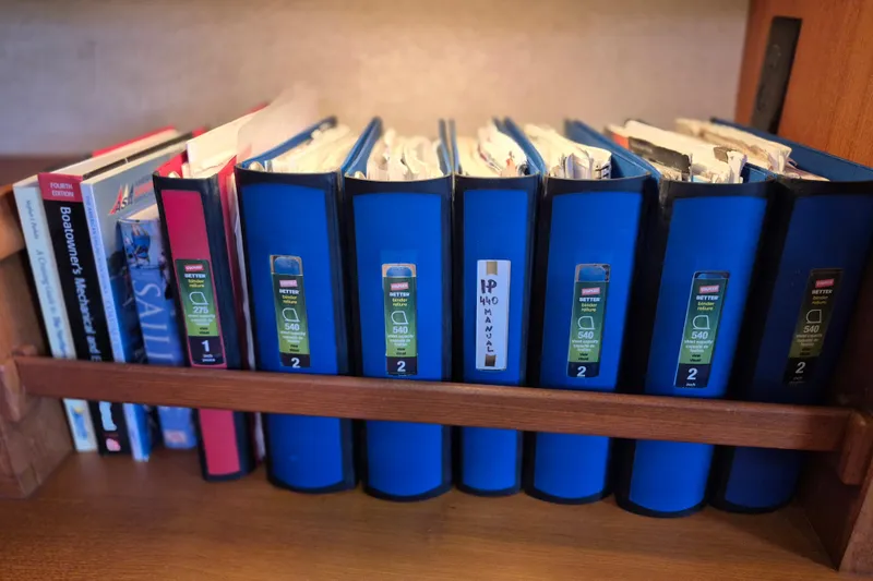 Mawe Yacht Photos Pics Books and binders on a shelf, including Island Packet 440 manual, 2006 model.