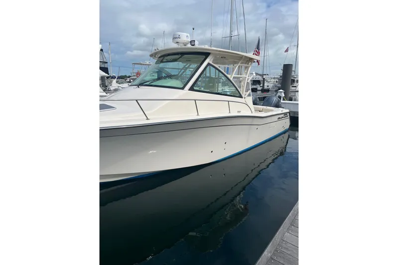 Between Wakes Yacht Photos Pics 2020 Grady-White Express 330 boat docked in marina, featuring sleek design and American flag.