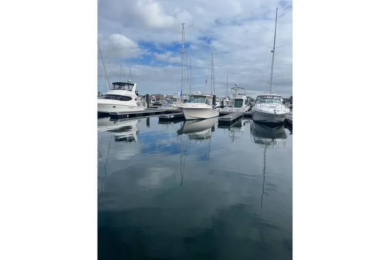 Between Wakes Yacht Photos Pics Boats docked at marina, featuring 2020 Grady-White Express 330 under cloudy sky.