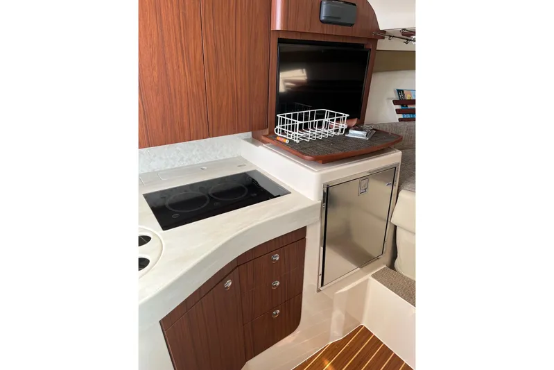 Between Wakes Yacht Photos Pics 2020 Grady-White Express 330 interior with kitchenette, stove, and storage cabinets.