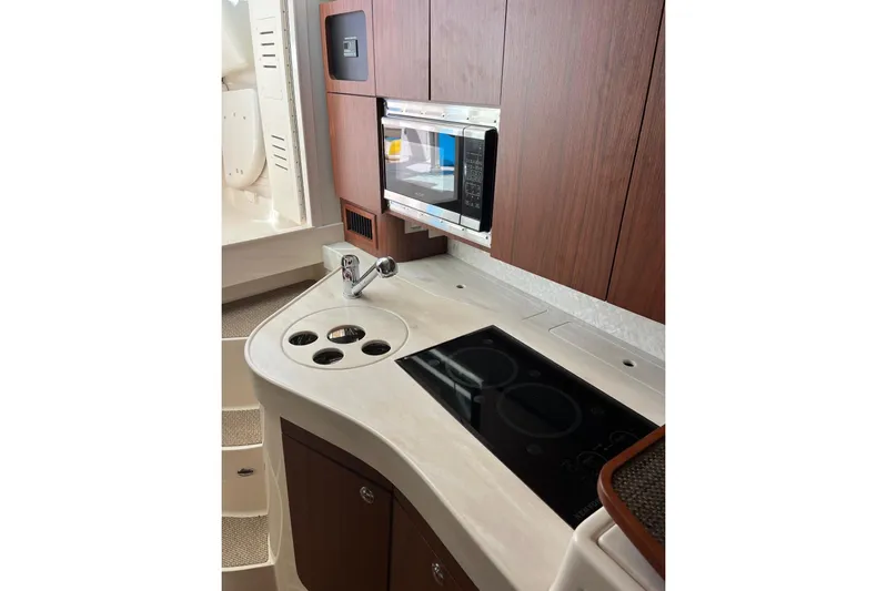 Between Wakes Yacht Photos Pics 2020 Grady-White Express 330 boat kitchen with microwave, stove, and wooden cabinets.