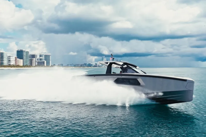 Mako Yacht Photos Pics 2024 Maori 46ft yacht speeding on ocean near city skyline under cloudy sky.