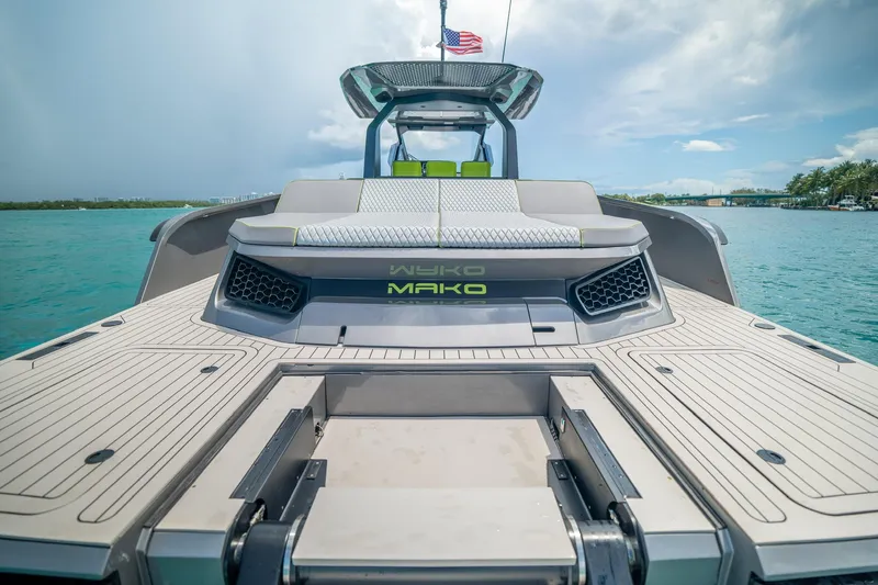 Mako Yacht Photos Pics 2024 Maori 46ft boat with sleek design on turquoise water, American flag waving.