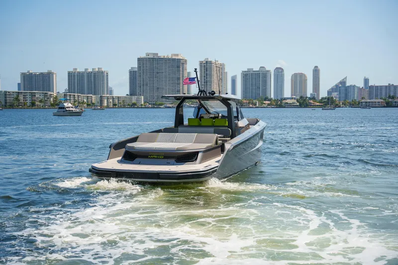Mako Yacht Photos Pics 2024 Maori 46ft yacht cruising near city skyline, clear blue water, and sunny skies.