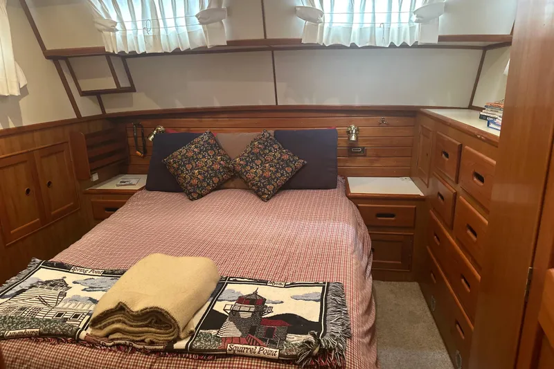 Phoenix Yacht Photos Pics Cozy cabin bedroom in 2000 Island Gypsy 36 yacht with wooden storage and decorative pillows.