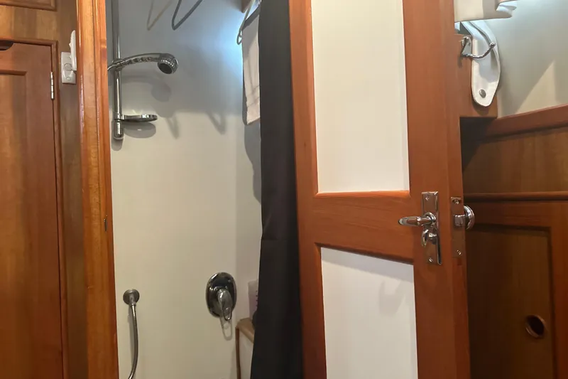 Phoenix Yacht Photos Pics Shower area inside 2000 Island Gypsy 36 boat, featuring wooden door and chrome fixtures.