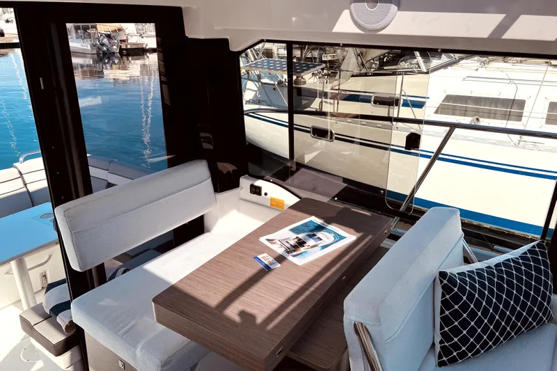 "halo" Yacht Photos Pics Interior of 2024 Jeanneau 8.95 boat with seating and table, docked at marina.