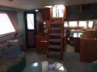 Interior of a 1990 Hi-Tech motor yacht with stairs, seating, and windows.