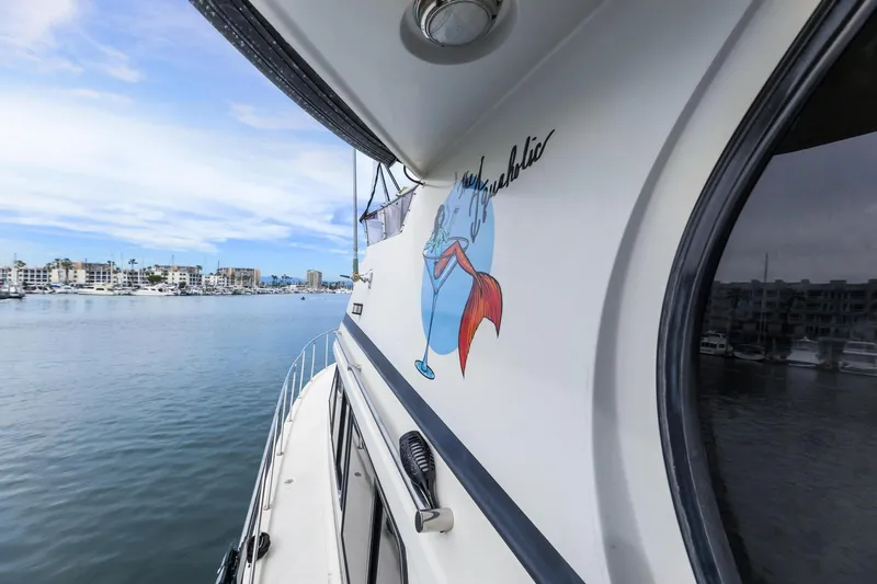 The Aquaholic Yacht Photos Pics 1988 Marine Trader Trawler on calm water, featuring a colorful mermaid graphic.