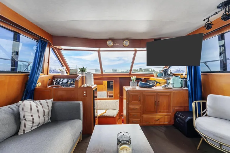 The Aquaholic Yacht Photos Pics 1988 Marine Trader Trawler interior with cozy seating, wooden cabinetry, and large windows.