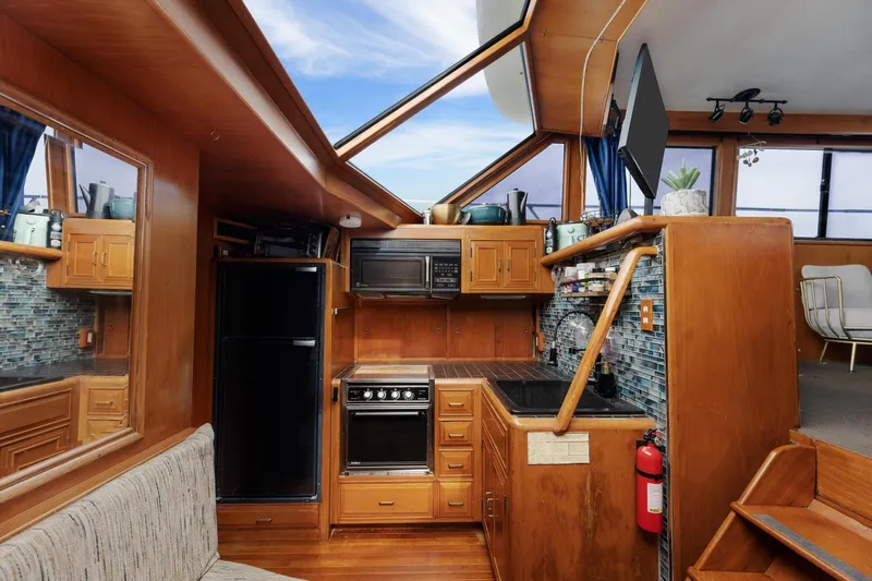 The Aquaholic Yacht Photos Pics 1988 Marine Trader Trawler kitchen with wood cabinetry, modern appliances, and skylight.