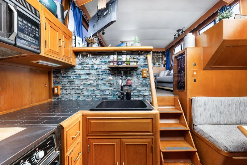 The Aquaholic Yacht Photos Pics 1988 Marine Trader Trawler kitchen with wood cabinetry, tiled backsplash, and black sink.