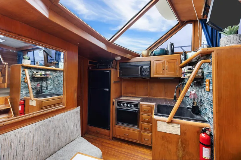 The Aquaholic Yacht Photos Pics 1988 Marine Trader Trawler interior with wooden cabinetry, kitchen appliances, and skylight.