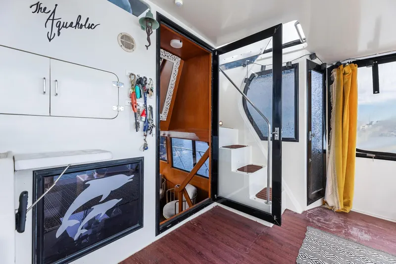 The Aquaholic Yacht Photos Pics 1988 Marine Trader Trawler interior with stairs, dolphin artwork, and nautical decor.