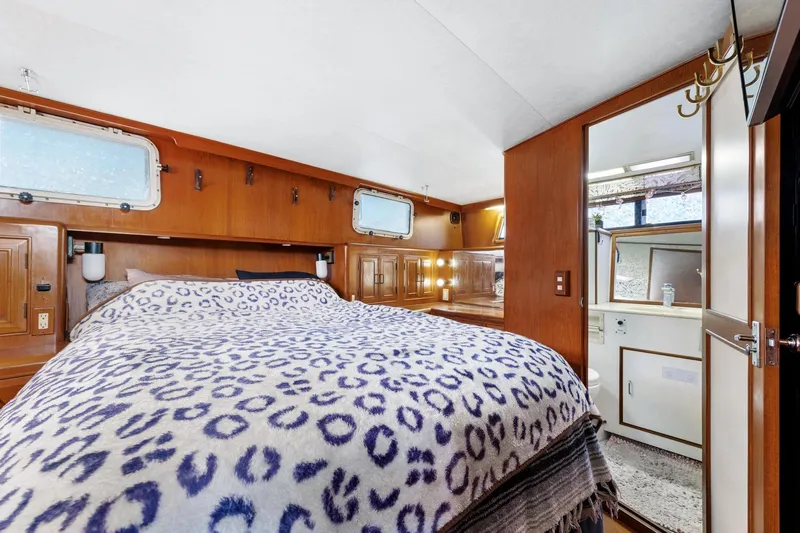 The Aquaholic Yacht Photos Pics 1988 Marine Trader Trawler bedroom with leopard print bedding and wooden interior.