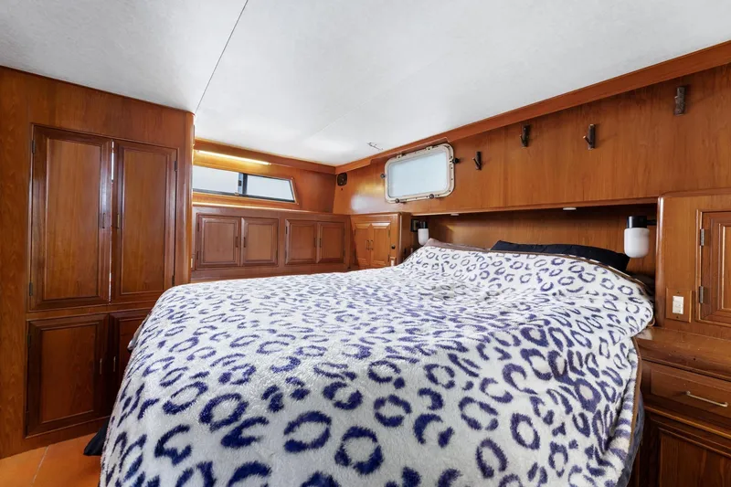 The Aquaholic Yacht Photos Pics 1988 Marine Trader Trawler cabin with cozy bed and wooden interior design.