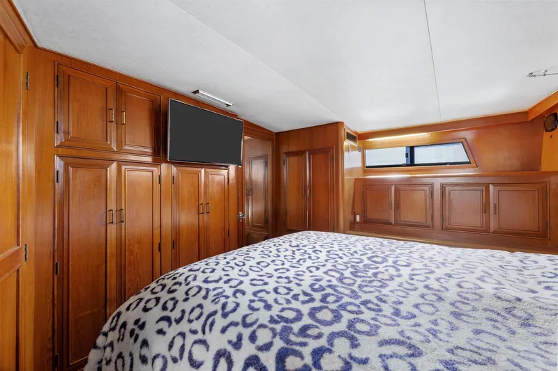 The Aquaholic Yacht Photos Pics 1988 Marine Trader Trawler bedroom with wood paneling, TV, and patterned bedspread.