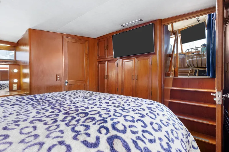 The Aquaholic Yacht Photos Pics 1988 Marine Trader Trawler bedroom with wooden cabinetry and patterned bedding.
