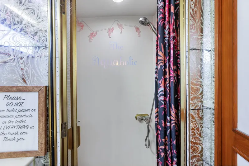 The Aquaholic Yacht Photos Pics Shower area in 1988 Marine Trader Trawler with decorative curtain and wall sign.