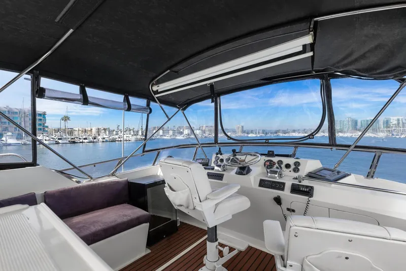 The Aquaholic Yacht Photos Pics 1988 Marine Trader Trawler helm with marina view, featuring navigation equipment and seating.