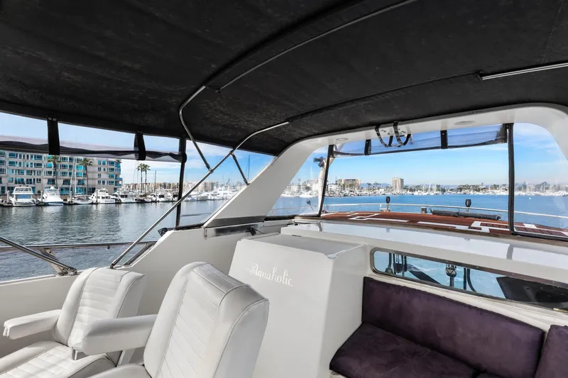The Aquaholic Yacht Photos Pics 1988 Marine Trader Trawler interior with marina view, featuring white seating and a covered deck.