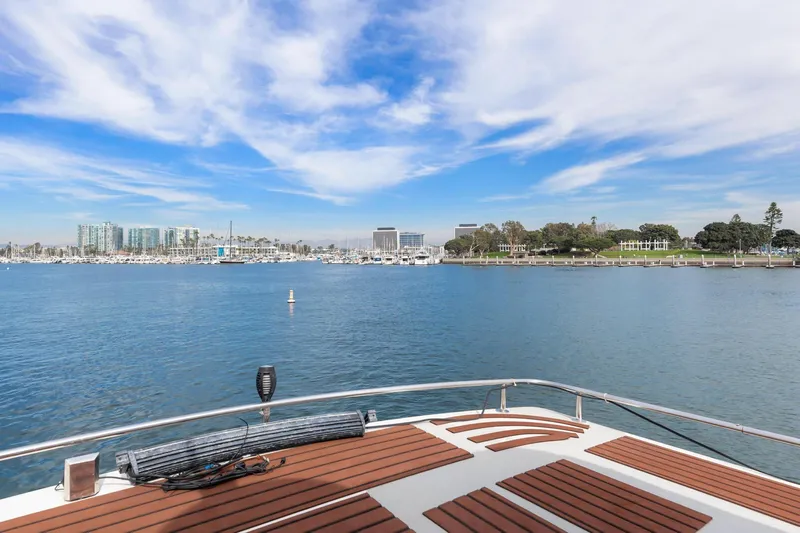 The Aquaholic Yacht Photos Pics 1988 Marine Trader Trawler on calm waters with cityscape and blue sky background.