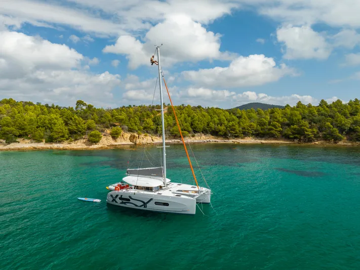 Tbd Yacht Photos Pics 2026 Excess 11 catamaran in turquoise waters near a wooded coastline.