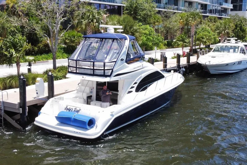  Yacht Photos Pics 2005 Sea Ray 420 Sedan Bridge yacht docked by lush greenery and waterfront.