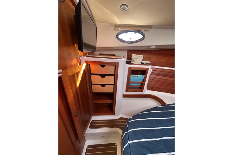 Fifth Child Yacht Photos Pics Interior of 2019 Back Cove 34O boat with wooden cabinetry and striped bedding.