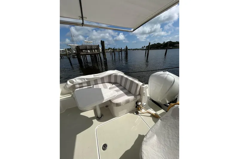 Fifth Child Yacht Photos Pics 2019 Back Cove 34O boat with striped seating, docked by calm waters.