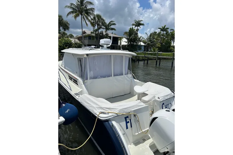Fifth Child Yacht Photos Pics 2019 Back Cove 34O boat docked by palm trees, featuring a covered deck and Garmin equipment.