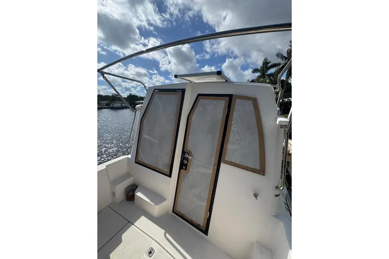  Yacht Photos Pics 2021 Ranger Tugs R-25 boat with cabin door, under a partly cloudy sky.