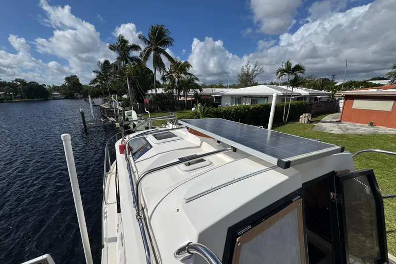 Yacht Photos Pics 2021 Ranger Tugs R-25 boat with solar panel, docked near waterfront homes and palm trees.