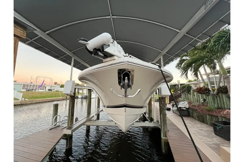  Yacht Photos Pics 2018 Regulator 28 boat on lift under canopy, docked by waterfront.