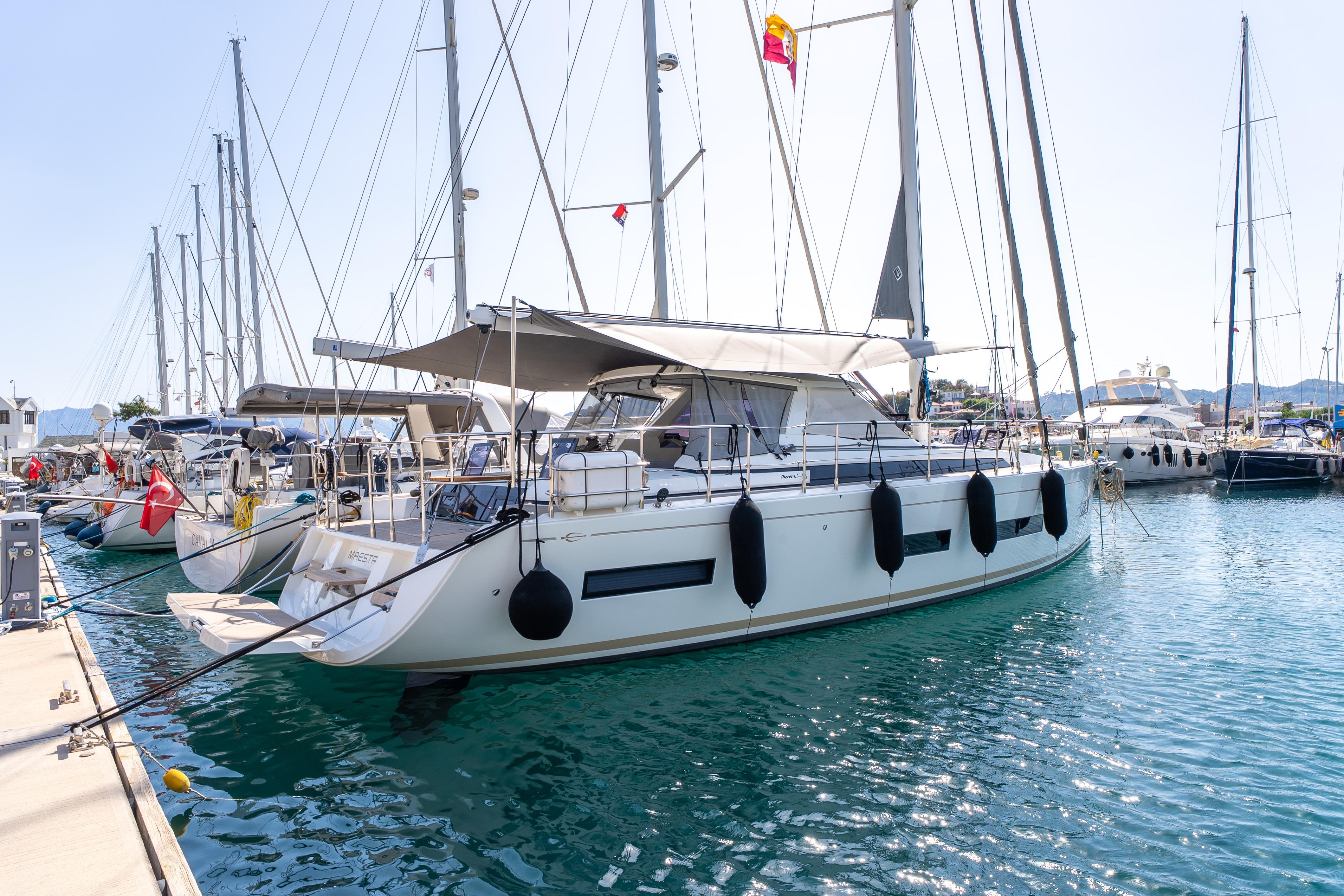 Sailing yacht Amel 50, 2019 model, docked in a marina with clear blue water.