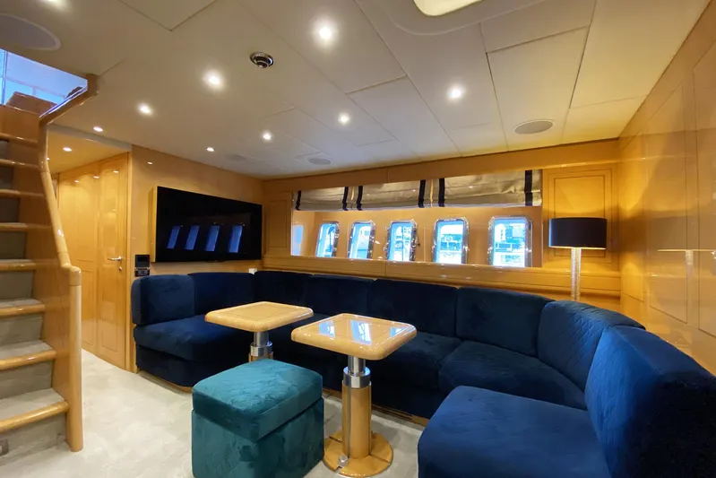 Querencia Yacht Photos Pics Luxurious interior of a 2004 Mangusta 72 Hardtop yacht with blue seating and wooden accents.