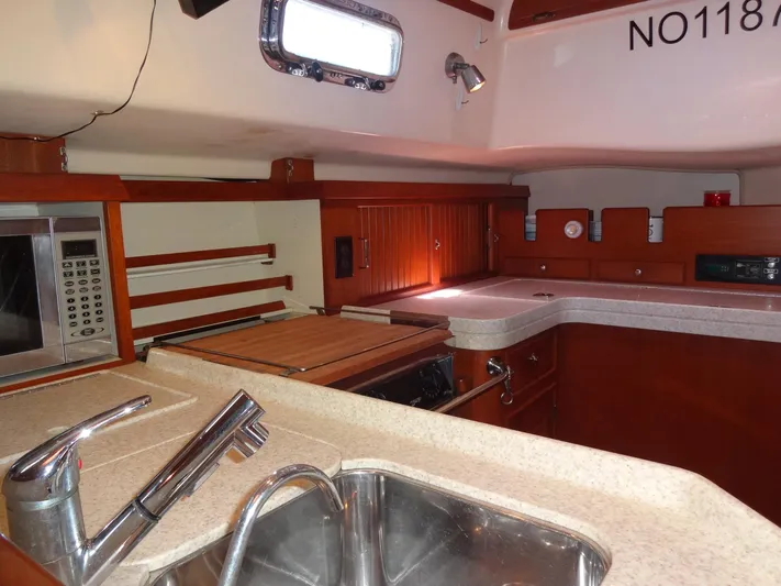 Don't Blink Yacht Photos Pics Interior of 2006 Island Packet 440 yacht kitchen with sink, microwave, and wooden cabinetry.