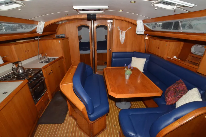 Misty Blue Yonder Yacht Photos Pics Interior of 1995 Jeanneau Sun Odyssey 45.1 yacht with wooden furnishings and blue seating.