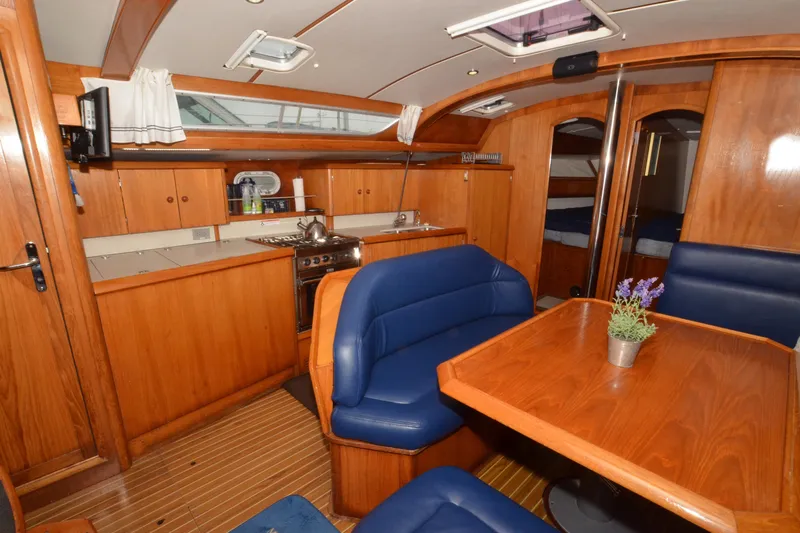 Misty Blue Yonder Yacht Photos Pics Interior of 1995 Jeanneau Sun Odyssey 45.1 yacht with wooden cabinetry and blue seating.