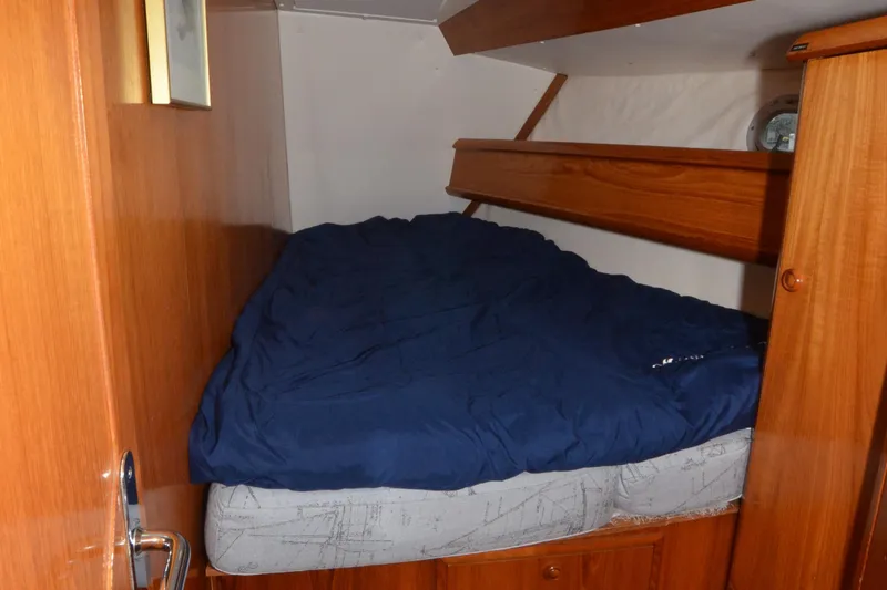 Misty Blue Yonder Yacht Photos Pics Cozy cabin interior of 1995 Jeanneau Sun Odyssey 45.1 with wooden finish and blue bedding.