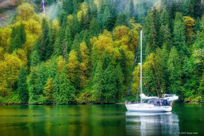 Misty Blue Yonder Yacht Photos Pics Jeanneau Sun Odyssey 45.1 sailboat on tranquil water, surrounded by lush green forest.