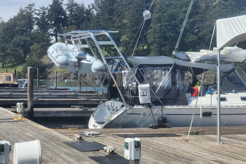 Misty Blue Yonder Yacht Photos Pics Jeanneau Sun Odyssey 45.1 sailboat docked, featuring a dinghy and lush forest backdrop.