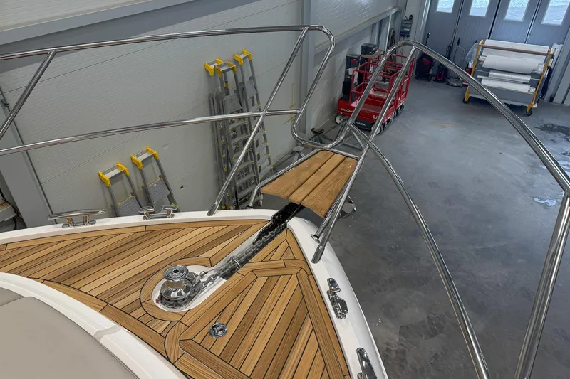 F45095 Yacht Photos Pics 2023 Princess F45 yacht bow with teak decking and stainless steel railings in a workshop.