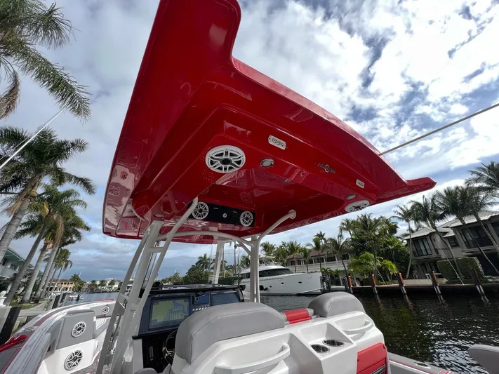 Havana Club Yacht Photos Pics 2023 Fountain 38 SC boat with red canopy, docked near palm trees and waterfront homes.